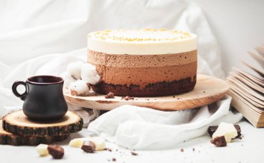 Beyaz arka plandaki ahşap tezgahta üç katmanlı çikolatalı mus keki. Taze kahve ve çikolatalı sufle ile günaydın. Eski arkaplan