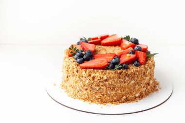 Bir sürü çıtır çıtır ekmek ve çilek ve böğürtlenle süslenmiş bal keki. Beyaz arkaplan