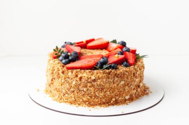 Bir sürü çıtır çıtır ekmek ve çilek ve böğürtlenle süslenmiş bal keki. Beyaz arkaplan