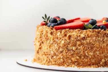 Bir sürü çıtır çıtır ekmek ve çilek ve böğürtlenle süslenmiş bal keki. Beyaz arkaplan