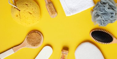 Banyo aksesuarlarının üst görüntüsü. Sarı arka planda çeşitli kişisel hijyen ve spa malzemeleri var.