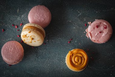 Koyu beton arka planda düz sarı ve pembe badem kurabiyeleri. Kırık Fransız tatlı kurabiyeli kırıntılı makro shot