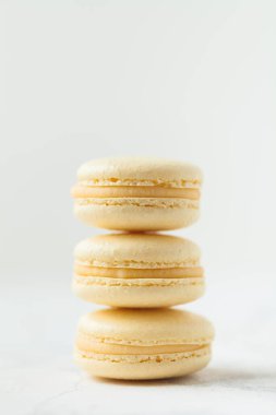 Beyaz arka planda sığ alan derinliği olan sarı badem kurabiyesi yığını. Fransız tatlı tatlı kurabiyeleri.