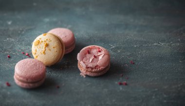 Koyu beton arka planda düz sarı ve pembe badem kurabiyeleri. Kırık Fransız tatlı kurabiyeli kırıntılı makro shot