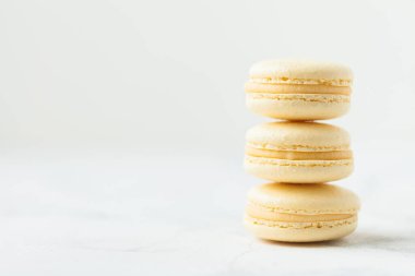 Beyaz arka planda sığ alan derinliği olan sarı badem kurabiyesi yığını. Fransız tatlı tatlı kurabiyeleri.