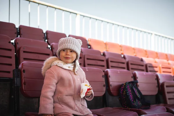 Cute Little Kaukaska Dziewczyna Jedzenia Frytki Stadionie Podczas Oglądania Meczu — Zdjęcie stockowe