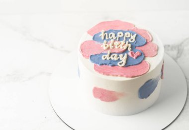 Krem peynirli beyaz pasta ve üstünde mutlu yıllar mesajı..