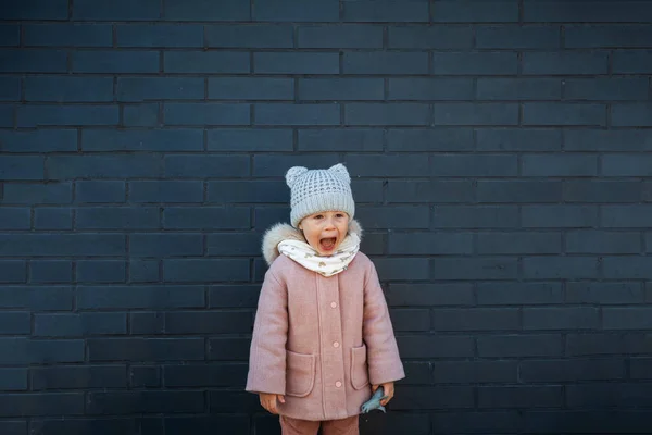 Cute Little Girl Krzycząc Głośno Przeciwko Ciemnej Cegły Ściany — Zdjęcie stockowe