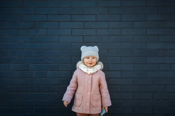 Sly Cute Little Girl Uśmiecha Się Ściany Ciemnej Cegły — Zdjęcie stockowe