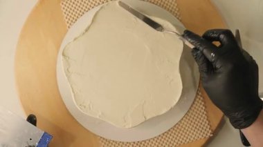 Pasta şefinin pasta tezgahını krem peynirle süslediği pasta poşeti ve spatulayla kapatmasını. Şekerlemecinin pastayı birleştirip süsleme süreci