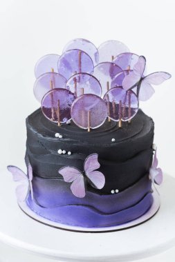 Yenebilir mor şeker kelebekleriyle süslenmiş menekşe çikolata kaplı güzel bir düğün ya da doğum günü pastası. Beyaz arkaplan