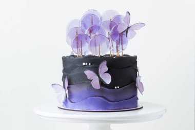 Yenebilir mor şeker kelebekleriyle süslenmiş menekşe çikolata kaplı güzel bir düğün ya da doğum günü pastası. Beyaz arkaplan