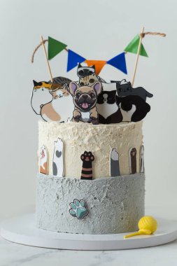 Beyaz arka planda yenilebilir köpek ve kedi figürleriyle süslenmiş güzel büyük bir doğum günü pastası. Küçük bir köpek ve kedi sever için kek.