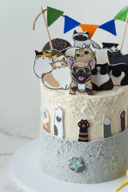 Beyaz arka planda yenilebilir köpek ve kedi figürleriyle süslenmiş güzel büyük bir doğum günü pastası. Küçük bir köpek ve kedi sever için kek.