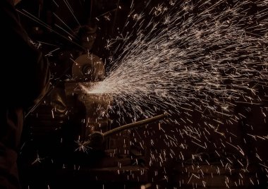 Mengeneye sıkıştırılmış metal bir iş parçası elektrikli bir aletle kesilir.