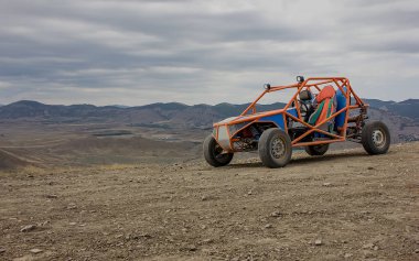 At arabası, dağların arka planında çakıllı bir yolda duruyor. Açık Gün