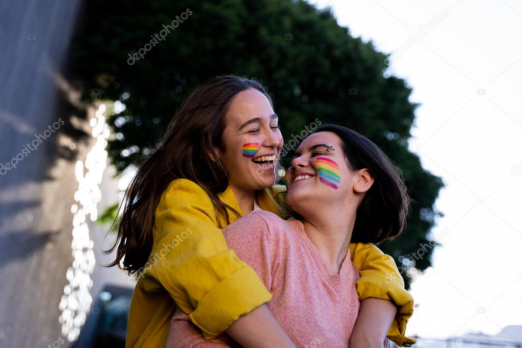 lesbian girls having fun painting themselves and with the lgtb flag on pride daylgtb concept