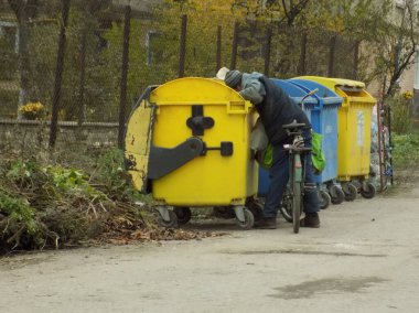 Çöp konteynırının yanındaki adam.
