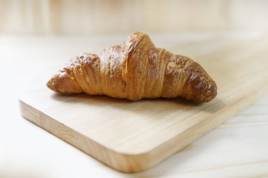 Lezzetli taze kruvasanlara odaklanmış. Ahşap hendek kazıcıda. Pencerelerden gelen yumuşak ışık.