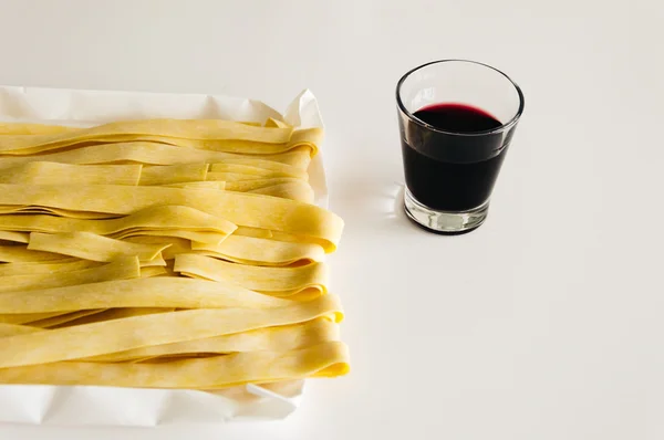 Färsk pasta och rödvin på vit bakgrund — Stockfoto