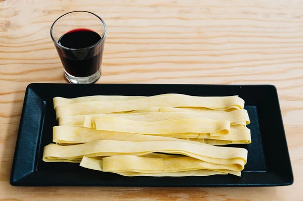 Färsk pasta och rödvin på träbord — Stockfoto