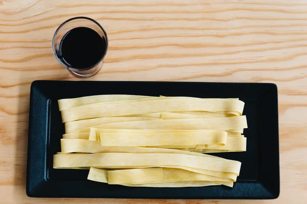 Färsk pasta och rödvin på träbord — Stockfoto