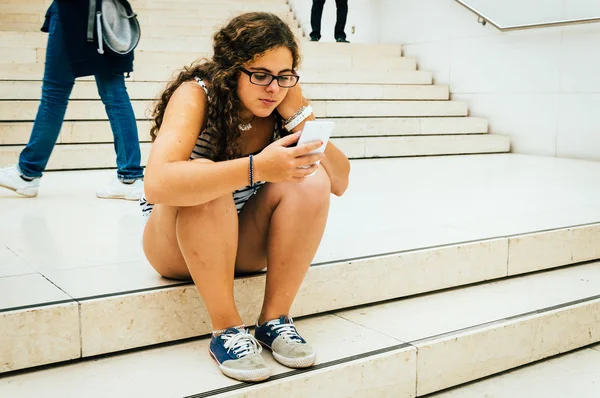 Молодая женщина на лестнице со смартфоном — стоковое фото