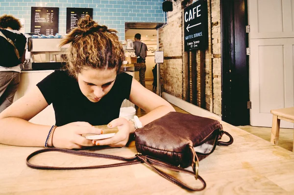 Young with a mobile phone in a cafe — Stock Photo, Image