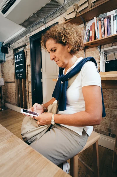 Woman in a cafe with her smartphone — Stock Photo, Image