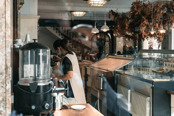 View through the window of a cafe with vintage decoration and a waitress preparing coffee — Stock Photo, Image