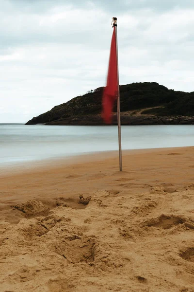 Vörös zászló lobogott a homokon a nyár felhős napján. — Stock Fotó
