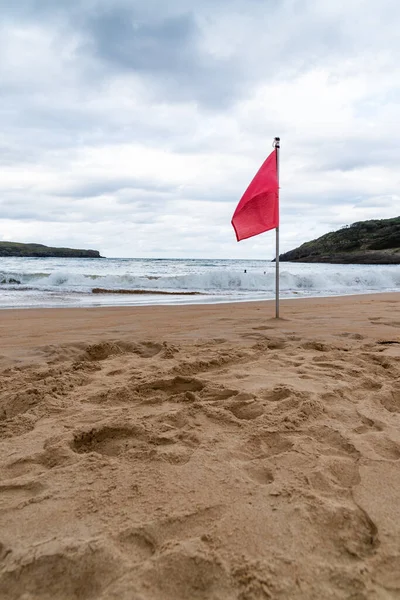 Vörös zászló lobogott a homokon a nyár felhős napján. — Stock Fotó