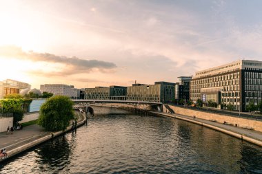 Günbatımında Berlin 'deki Spree Nehri' nin kıyısındaki modern ofis binalarının panoramik manzarası