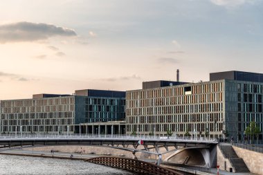 Günbatımında Berlin 'deki Spree Nehri' nin kıyısındaki modern ofis binalarının panoramik manzarası