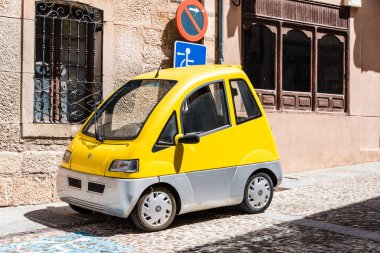 Caddeye park edilmiş küçük sarı elektrikli araba.