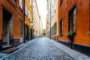 Stockholm 'deki Gamla Stan' de eski renkli evlerin arasında güzel, eski bir kaldırım taşlı cadde.