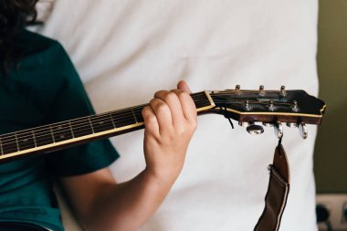 Kadın eli akustik gitarda çalıyor, yakın plan.