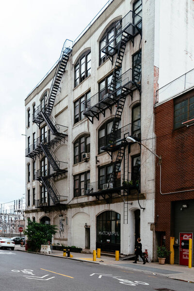 New York City, USA - June 24, 2018: Traditional Brooklyn building with fire escapes and Matchaful hipster cafe