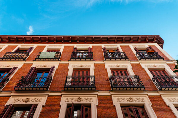 Low angle view of old recently renovated residential building against blue sky. Madrid, Spain