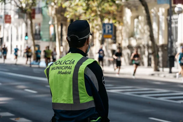 Policista sleduje průběh závodu v ulicích města. — Stock fotografie