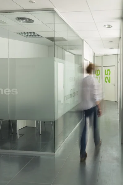 Bulanık bir modern ofis binası koridorda yürüyen bir kadın figürü