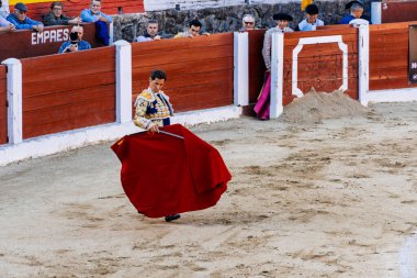 Arenas de San Pedro, İspanya - 18 Ekim 2025: Matador bir koridor sırasında arenada kırmızı bir muleta ile boğaya karşı karşıya. Cesar Jimenez