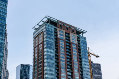 Chicago, ABD - 13 Nisan 2025: Çağdaş mimarinin yer aldığı Chicago kentsel peyzaj ve gökyüzüne karşı büyük bir kule vinci