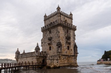 Lizbon, Portekiz - 29 Ekim 2022: Belem Kulesi Lizbon, Portekiz 'de bulutlu bir gökyüzüne karşı karmaşık mimarisini gözler önüne seriyor..