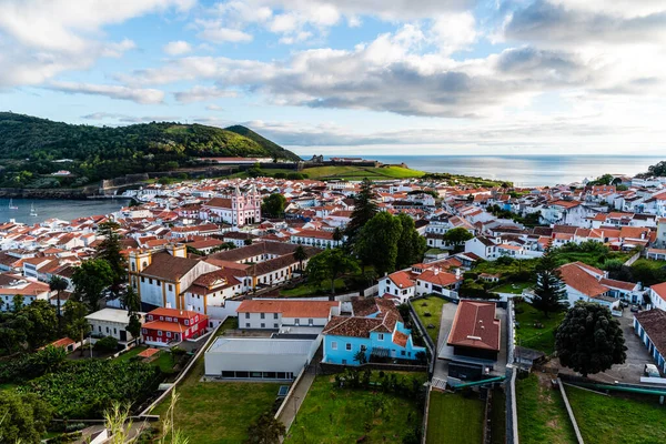 Angra do Heroismo, Terceira, Azores 'in manzarası, bulutlu bir gökyüzü altında şehir mimarisini ve kıyı manzarasını gösteriyor..