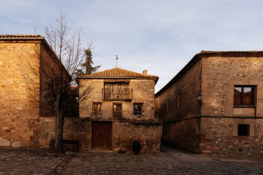 Medinaceli, Soria. Çakıl taşı caddesi boyunca terracotta çatı kiremitleri olan geleneksel taş ev. Ortaçağ köyü
