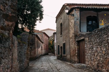 Medinaceli, Soria. Çakıl taşı caddesi boyunca terracotta çatı kiremitleri olan geleneksel taş ev. Ortaçağ köyü