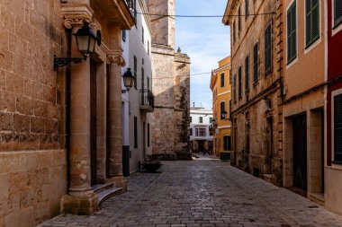 Güneşli bir günde İspanya 'nın Ciudadela, Menorca, Balearic Adaları' nda beyazlatılmış binalar ve ahşap panjurlarla dolu pitoresk dar kaldırım taşı yolu.