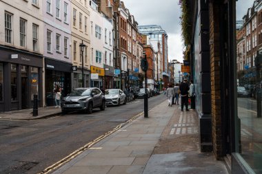 Londra, İngiltere - 27 Ağustos 2023: Bulutlu bir günde Londra 'nın Soho bölgesinde dükkanları, arabaları ve yayaları olan bir caddenin manzarası.