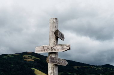 Kırsal bir ahşap levha, Sao Miguel, Azores 'de bulutlu bir gökyüzünün altında, farklı noktaların yönlerini gösterir..